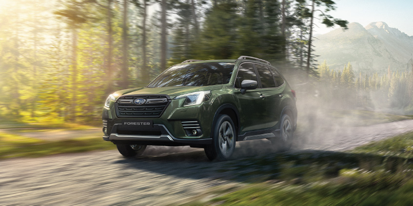 Camioneta Subaru Forester en tono verde oliva metálico, a velocidad en bosque.