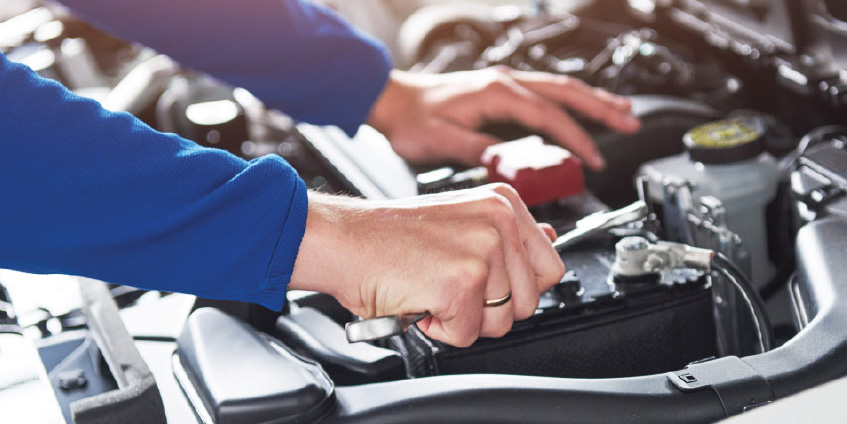 Manos de hombre mecánico realizando mantenimiento preventivo a auto.